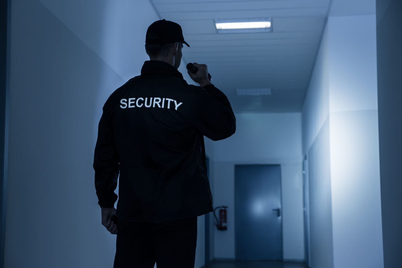 A security guard is standing in the hallway of an office building.